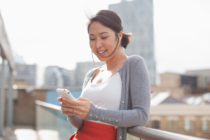 Smiling businesswoman text messaging with cell phone