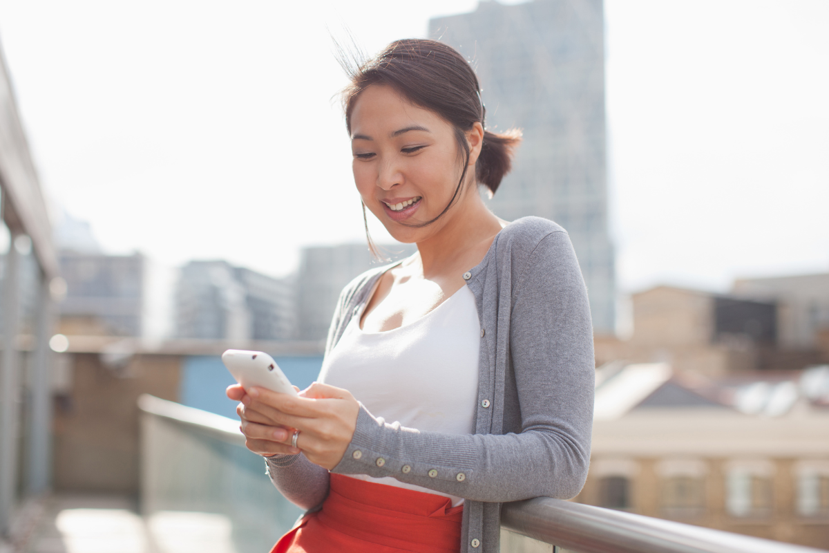 Smiling businesswoman text messaging with cell phone