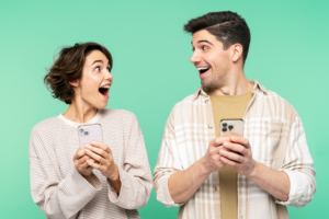 Surprised Couple Holds Mobile Phones Green Background