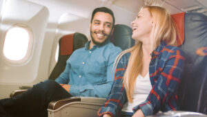 Passengers smiling while seated on a plane.
