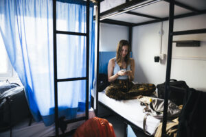 Woman sitting on bed in hostel.
