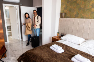 Couple entering hotel room with suitcase.