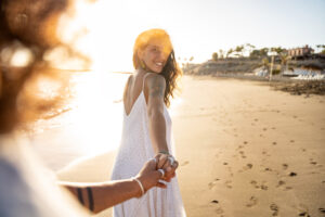 Couple Walk Along Beach, Woman Looks Back