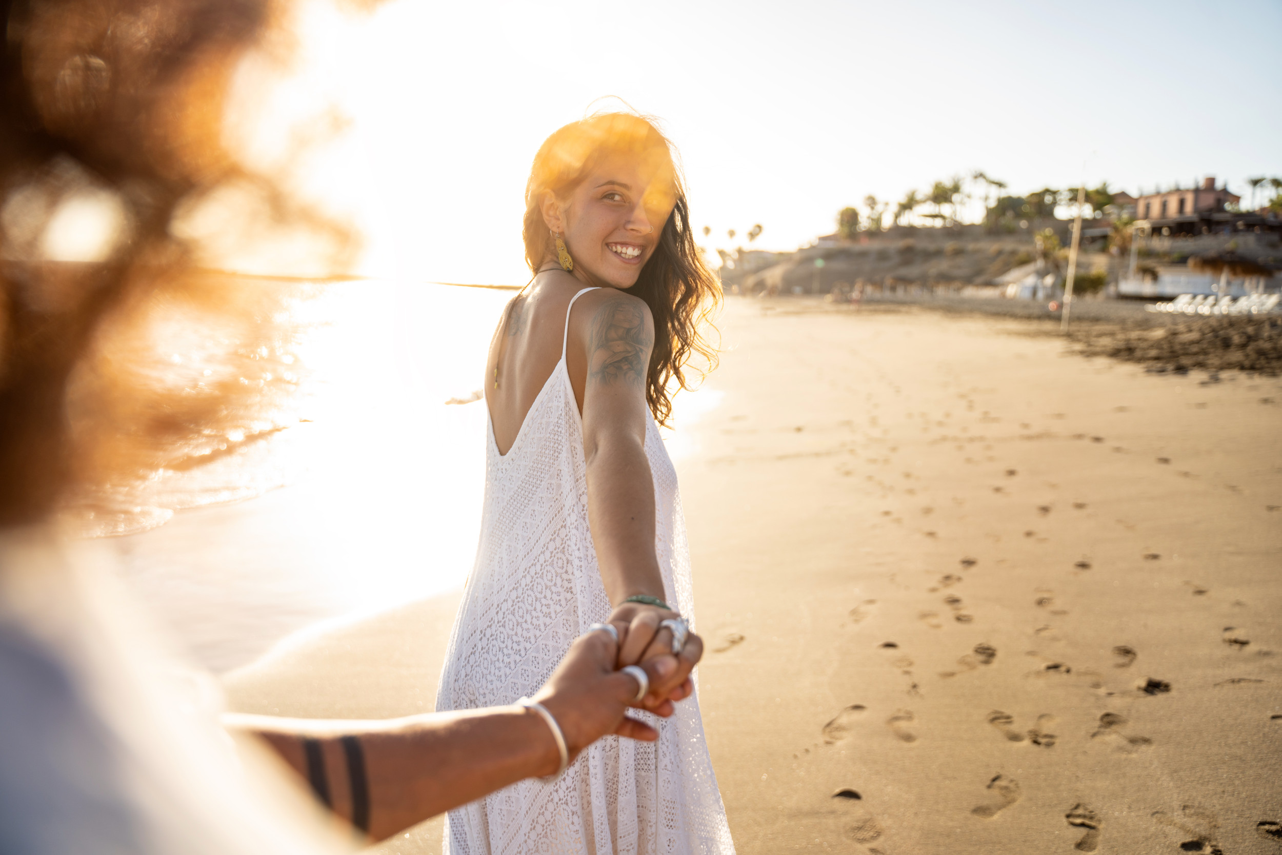 Couple Walk Along Beach, Woman Looks Back